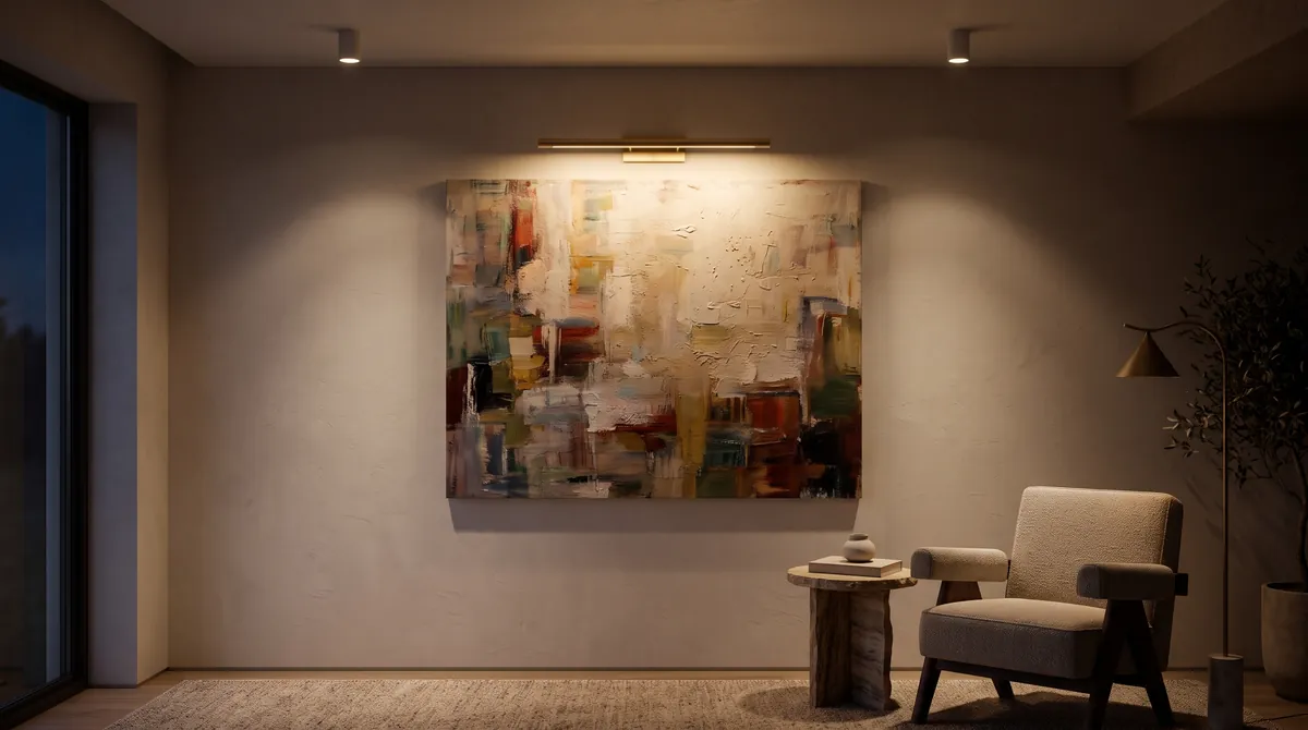 Ein Gemälde im abendlichen Wohnzimmer, beleuchtet von einer schlanken Bilderleuchte aus Messing